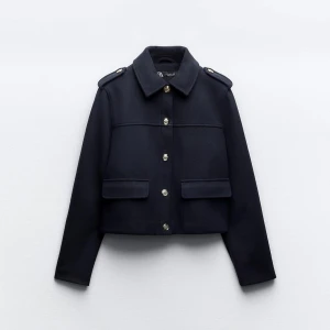 Oanvänd marinblå jacka med knappar - Snygg marinblå kavajjacka från Zara med guldknappar och axelklaffar. Jackan har en croppad passform och två stora fickor. Prislapp sitter kvar