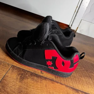 DC skor strl 36.5 - Snygga svarta sneakers från DC med röd/rosa sula. Använda men fortfarande fina, skicka dm för flera bilder