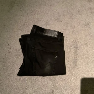 Svarta jeans från Replay - Snygga svarta jeans från Replay med klassisk design. De har en normal passform och är perfekta för en stilren look. Jeansen har en dragkedja och knapp framtill samt fickor både fram och bak.