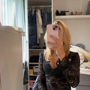 Svart spetsblus - Säljer en elegant svart spetsblus med långa ärmar och v-ringad design. Perfekt för en stilfull look.