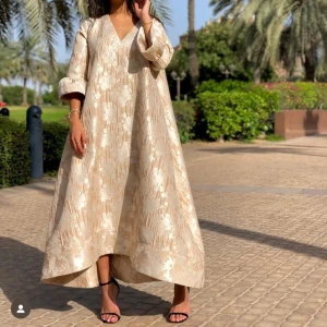 Exklusive klänning från Dubai  - Elegant beige långklänning med v-ringad hals och trekvartsärmar. Klänningen är i väldigt bra material och köpt i Dubai för ca 3000 kr. Passar S/M . Guld/beige färg! 