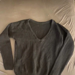 Svart ribbad tröja från NA-KD - Säljer en stilren svart ribbad tröja från NA-KD. Tröjan har en v-ringad hals och långa ärmar, perfekt för kyligare dagar. Den är både bekväm och trendig, ett måste i garderoben!