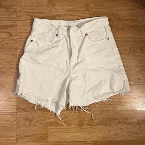 Vita jeansshorts med fransar - Snygga vita jeansshorts med fransiga kanter och klassisk femficksdesign. Perfekta för en avslappnad sommarlook.