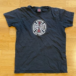 Svart t-shirt från Independent Truck Company - Säljer en svart t-shirt från Independent Truck Company med deras ikoniska logga i vitt och rött på bröstet. T-shirten är kortärmad och perfekt för vardagsbruk. Passar barn i åldern 10-12 år.