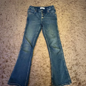 Blå bootcut jeans från Zara - Säljer snygga blå bootcut jeans från Zara med knappar framtill.  Har täcken på användning. Hör av er om ni har några frågor!💜💜