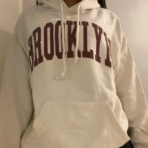 Vit hoodie med Brooklyn-tryck - Säljer en vit/ créme hoodie i storlek s med texten 'BROOKLYN' i mörkrött på bröstet. Den är i jättebra skick då jag aldrig har använt den och den sitter jättegulligt på då passformen också är lite avslappnad❤️priset kan diskuteras.