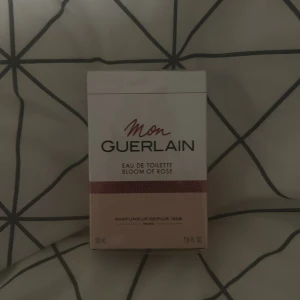 Mon Guerlain Bloom of Rose Eau de Toilette helt ny  - Mon Guerlain Bloom of Rose Eau de Toilette är en elegant och feminin doft från Guerlain. Förpackningen är stilren med en vit och rosa design. Denna parfym hyllar modern kvinnlighet med en blommig och fräsch doftprofil.