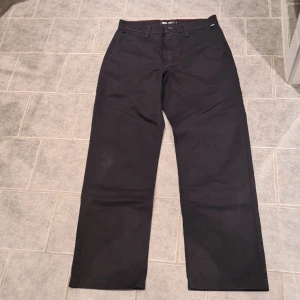 Svarta chinos från Vans - Säljer ett par svarta Vans Authentic Chino byxor i loose fit. Byxorna har en klassisk design med knappar bak och dragkedja fram. Perfekta för en avslappnad stil. Storlek 31. Har inga skador eller slitningar.
