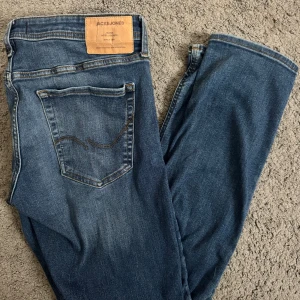 Blå jeans från Jack & Jones - Snygga blå jeans från Jack & Jones med klassisk femficksdesign och en bekväm passform. Perfekta för en avslappnad stil. Märkeslappen i läder ger en extra touch av stil.