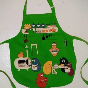 Färgglatt Barbapapa förkläde i grönt.  - Säljer ett unikt färgglatt Barbapapa förkläde i grönt. Perfekt att ha till julstöket och precis alla andra tillfällen. Det är gjort av ett slitstarkt material och kanske använd en gång. Den är alltså som helt ny och himla charmig. 