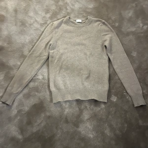 Beige kashmirtröja från Asket - Säljer en stilren beige tröja från Asket i mjuk kashmirblandning. Tröjan har en klassisk rund hals och långa ärmar med ribbade muddar. Perfekt för kyligare dagar.