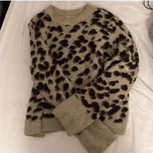Leopardmönstrad stickad tröja - Säljer en snygg beige stickad tröja med leopardmönster. Tröjan har långa ärmar och ribbade muddar vid ärmslut och nederkant. Köpt av en annan plickare, kommer inte längre till användning.🫶🏼