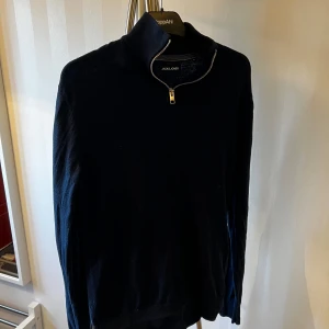 Mörkblå tröja med dragkedja från Jack & Jones - Säljer en stilren mörkblå tröja från Jack & Jones med dragkedja vid halsen. 