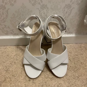 Vita klackskor med remmar - Eleganta vita klackskor med breda korsade remmar och justerbart spänne runt ankeln. Testad bara✨