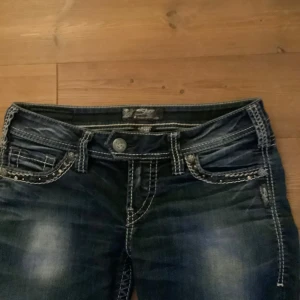 Mörkblå jeans med dekorativa sömmar - Snygga mörkblåa liknande missme jeans. Dem har vita sömmar och detaljrika fickor med små rhinestones.