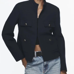 Marinblå Zara jacka  - Snygg marinblå jacka med stilrena knappar framtill. Den har en klassisk design med långa ärmar och två fickor med lock. Perfekt för en chic och elegant look.