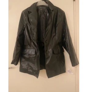 Svart skinnjacka från Bershka - Snygg svart skinnjacka från Bershka med knappar framtill och klassisk krage. Jackan har långa ärmar och två fickor. Perfekt för en stilren look. Oanvänd med prislapp på🩵