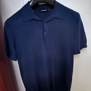 Mörkblå pikétröja från J.Lindeberg - Snygg mörkblå pikétröja från J.Lindeberg. Tröjan har en klassisk krage och knappar framtill. Perfekt för en stilren look. 10/10 skick. Köpt för 800