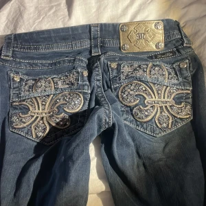 Blå jeans med broderade detaljer från Miss Me - Säljer för jag behöver pengar❤️❤️Snygga blå jeans från Miss Me med unika broderade detaljer och glittriga inslag på bakfickorna. Jeansen har en klassisk femficksdesign.. Perfekta för dig som vill ha något extra i garderoben!
