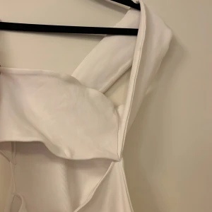 Vit ärmlös klänning - Elegant vit ärmlös klänning med en stilren design. Klänningen har en omlott-detalj och är tillverkad i ett mjukt material som ger en bekväm passform. Perfekt för sommarens alla tillfällen.