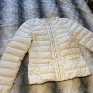 Vit pufferjacka från Holly & Whyte - Säljer en stilren vit pufferjacka från Holly & Whyte by Lindex. Jackan har en dragkedja framtill och är perfekt för kyligare dagar. Den har en normal passform och långa ärmar.