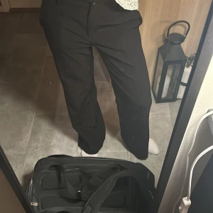 Svarta kostymbyxor - Snygga svarta kostymbyxor med hög midja och rak passform. Perfekta för en stilren look. Byxorna har en klassisk design som passar till många olika tillfällen.