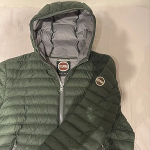 Grön colmar jacka - Snygg grön  dunjacka från Colmar med huva och dragkedja. Perfekt för kyligare dagar med sin stilrena design och praktiska fickor med dragkedjor. Jackan har en normal passform och är långärmad. 