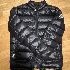 Moncler Acorus - Snygg svart dunjacka från Moncler med dragkedja och hög krage. Perfekt för kyliga dagar och ger en fräsch look. Jackan är köpt samma vinter men passade inte mina behov. Kvitto finns, QR funkar. Storlek 1-S. Skriv bara om intresserad.