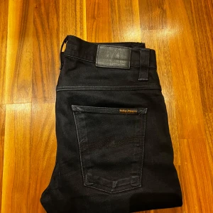 Svarta jeans från Nudie Jeans - Säljer ett par svarta jeans från Nudie Jeans i modellen Grim Tim i storlek 31/32. Perfekta för en stilren look. I ett mycket bra skick.