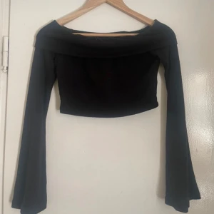 Svart offshoulder topp - Snygg svart offshoulder topp med långa ärmar och croppad design. Perfekt för en stilren look.