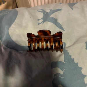 Brun hårklämma - Snygg brun hårklämma i sköldpaddsmönster. Perfekt för att hålla håret på plats med stil. Klämman har en stark fjädermekanism för bra grepp.