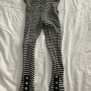 Randiga byxor från Polarn O. Pyret - Säljer ett par randiga byxor från Polarn O. Pyret i svart och vitt. Byxorna har en bekväm elastisk midja och knappar vid bensluten för extra stil. Perfekta för en cool och avslappnad look. Varan kommer att tvättas och strykas innan leverans! ⭐️