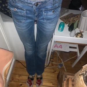 Blå jeans med knappar - Säljer ett par snygga blå jeans med knappar framtill och fickor med lock.💘 Jeansen innerbenslängd är 75cm.💝 Och midjemåttet är justerbar.☀️ Dom är från Gina Tricot Young men skulle säga att dom passar XS! Skriv om ni har några funderingar 💕frakt=40kr💘 priset kan diskuteras 💕 betalning via swish❤️och dom är i ganska bra skick, har tvättat dom en gång 