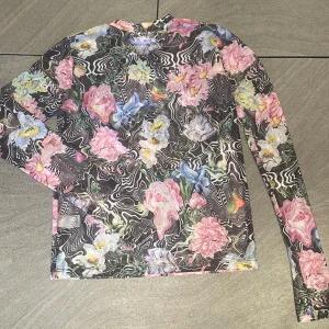 New Junkyard flowery black mesh top,size S - Säljer en färgglad och unik långärmad topp från Junkyard med ett blommigt mönster i rosa, blått och gult. Perfekt för att liva upp garderoben med lite färg och stil. 🌸Tagprice:199 kr but sell for 90kr
