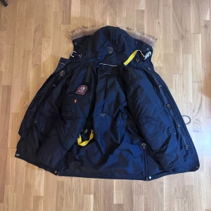 Parajampers jacka - Snygg svart parkajacka från Parajumpers med pälsdetaljer på huvan. Jackan har flera praktiska fickor och en robust dragkedja. Perfekt för kalla dagar med sin varma vaddering och stilrena design. Storlek M. Kemtvättad, och i superskick. 