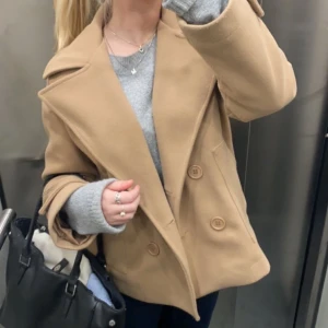 Beige kappa med knappar - Snygg beige kappa med stora knappar och bred krage. Den har en klassisk design med två stora fickor framtill. Storlek xs-s men passar nog m oxå. Den är i bra skick och har använts varsamt 