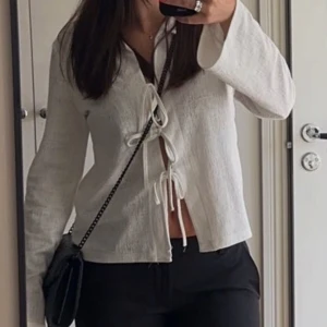 Top med knytning  - En fin top med trumpetärmar och med knytning i mitten. Säljes då den inte längre kommer till användning. Använd ca 3 gånger.