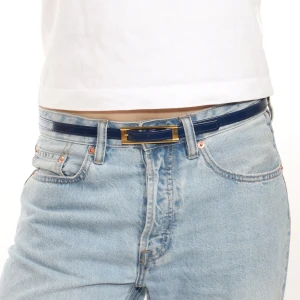 Blått bälte med gulddetaljer - Snyggt blått bälte med elegant guldfärgat spänne. Perfekt för att ge en stilren touch till din outfit. Passar utmärkt till jeans och andra byxor.