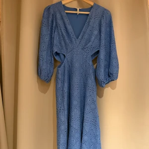 Blå klänning från Object - Snygg blå klänning från Object med v-ringning och vackert spetsmönster. Klänningen har trekvartsärmar och en elegant öppen ryggdetalj. Perfekt för en stilfull look.