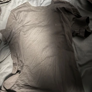 Svart t-shirt från Hugo Boss - Snygg svart t-shirt från Hugo Boss med diskret logga på bröstet. Perfekt för en stilren look. Tillverkad i mjukt material för extra komfort.