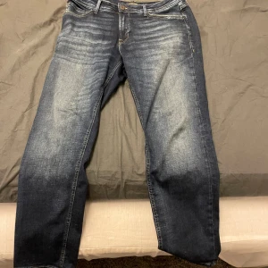 Mörkblå jeans från Jack & Jones - Säljer ett par mörkblå jeans från Jack & Jones i modellen Regular/Clark. De har en klassisk femficksdesign och en bekväm passform. Perfekta för en avslappnad stil.