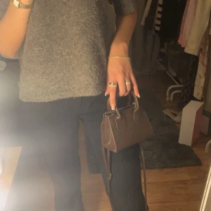 Brun axelväska - Snygg brun axelväska i skinn med stilrena handtag och justerbar axelrem. Perfekt för att bära det viktigaste med stil. Enkel och elegant design som passar till många olika outfits.