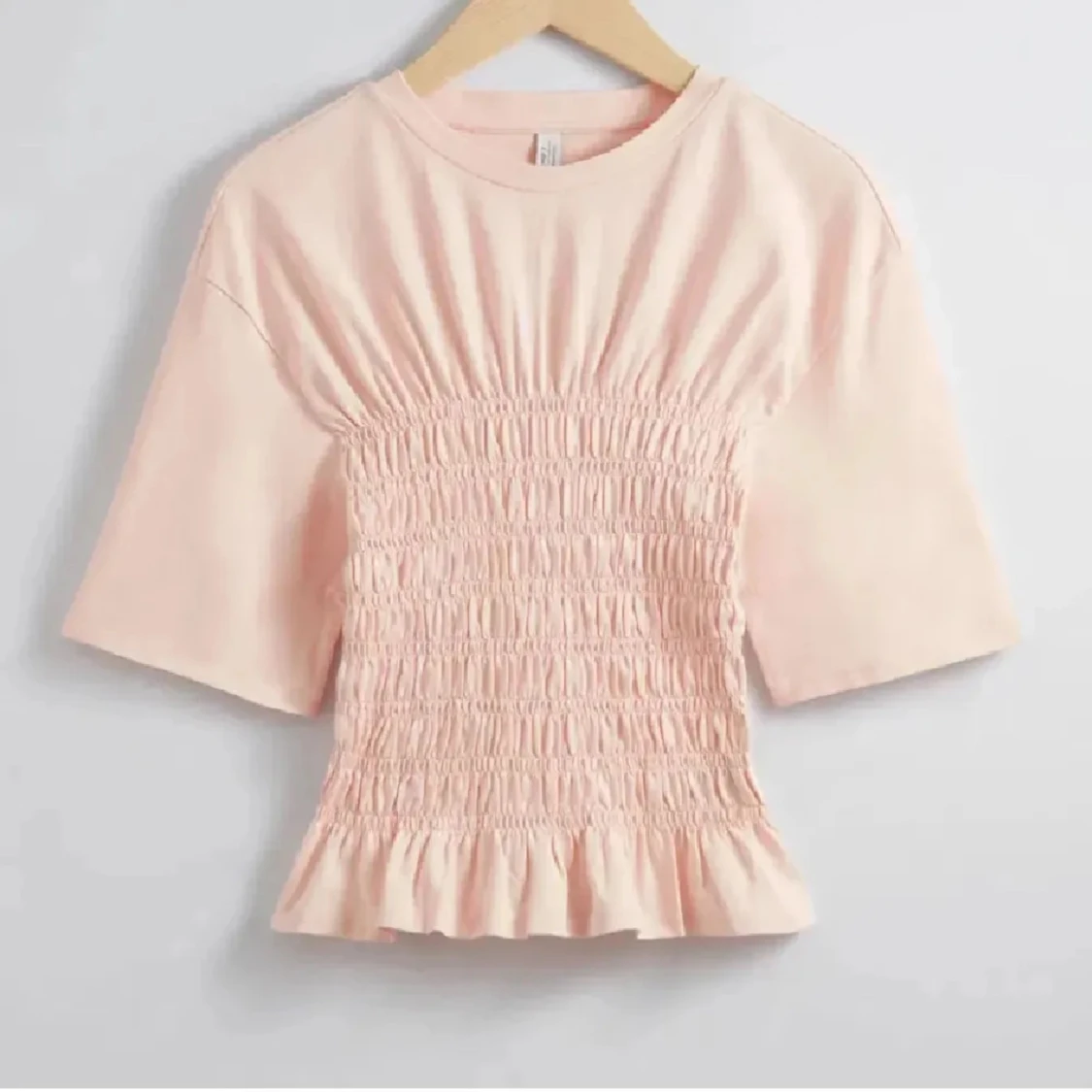 Ljusrosa topp med smockdetaljer