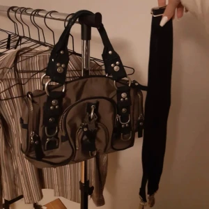 Brun George gina & Lucy väska med nitar  - Snygg brun axelväska med svarta handtag och coola nitar. Väskan har flera dragkedjor och detaljer i metall som ger en tuff look. Perfekt för att ge din outfit en edgy touch. Fråga om mer info!!! Den är som ny och priset kan diskuteras💋