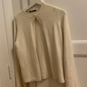 Beige kofta från Gina Tricot - Säljer en stilren beige kofta från Gina Tricot i storlek XS. Koftan har en enkel knapp framtill och ribbade kanter vid ärmslut och nederkant. Perfekt för lager-på-lager under kyligare dagar. Pris kan diskuteras!