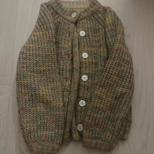 Mönstrad stickad kofta med knappar - Säljer en mysig stickad kofta i jordnära toner med stora knappar framtill. Perfekt för kyliga dagar med sin varma och bekväma design. Koftan har långa ärmar och ribbade kanter. 🩷