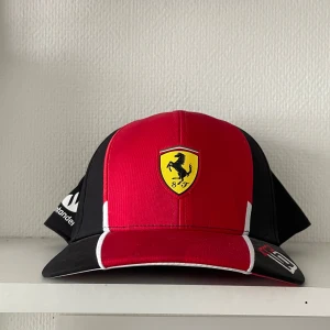 F1 Ferrari-Charles Leclerc keps  - F1 Ferrari Charles Leclerc keps säljes i fint och oanvänt skick. PUMA Skickas mot fraktkostnad. 250 kr