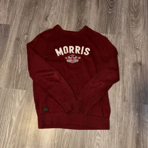 Vinröd tröja från Morris - Säljer en snygg vinröd tröja från Morris med text och emblem på bröstet. Tröjan har långa ärmar och ribbade muddar vid ärmslut och nederkant. Perfekt för en stilren look. Den är i storlek m men sitter som s