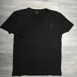 Svart Ralph Lauren T-Shirt  - Säljer nu denna riktigt snygga Ralph Lauren T-shirten. Väldigt fint skick. Storlek L. Nypris ca 699&, mitt pris endast 325kr. Hör av dig om du undrar något eller vill ha fler bilder! Pris är diskuterbart vid snabb affär🤝