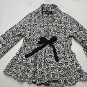 Kofta - Säljer en snygg svartvit Odd Molly LIKNANDE kofta från Chelsea med ett detaljerat mönster! Koftan har långa ärmar och en dekorativ rosett framtill. Perfekt för att ge din outfit en stilfull touch.